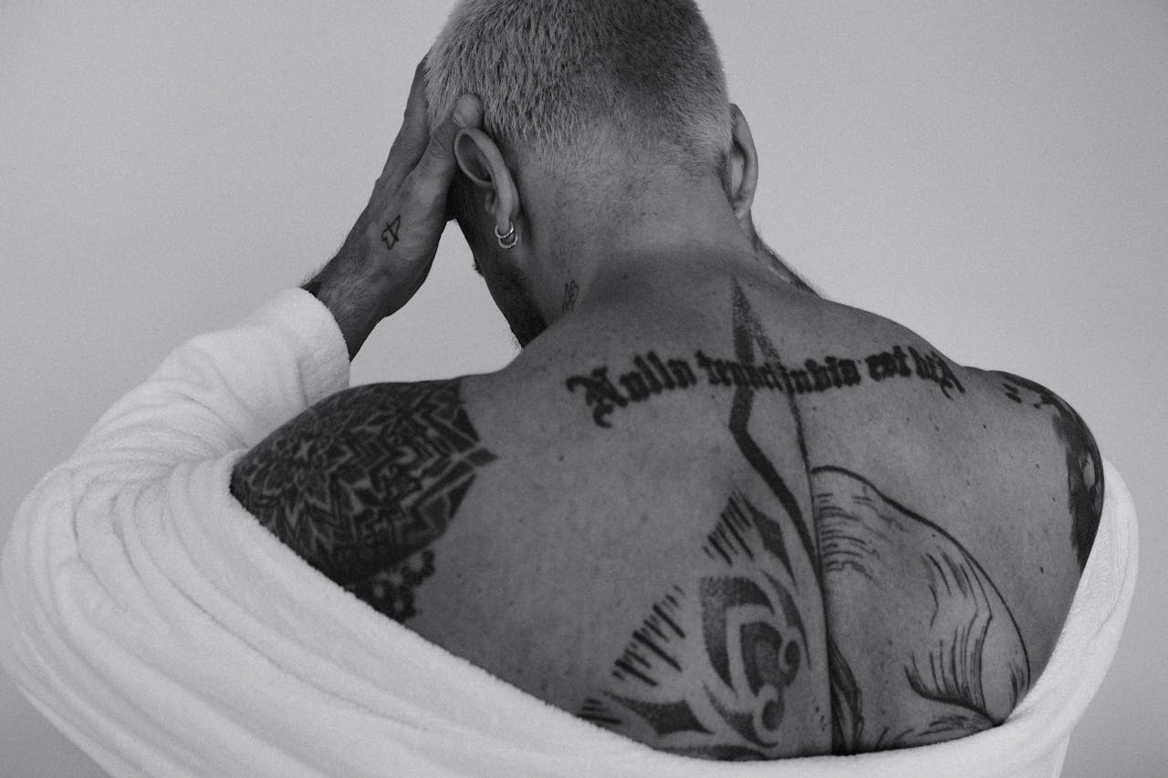 Back view of a tattooed man in monochrome, emphasizing artistic body art.